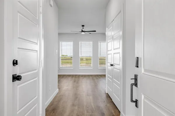 a view of a hallway with wooden floor and a bathroom