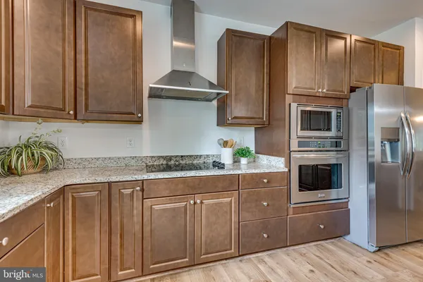 a kitchen with granite countertop a refrigerator stove and cabinets