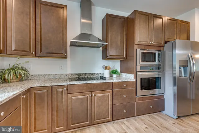 a kitchen with granite countertop a refrigerator stove and cabinets