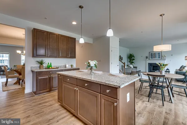 a kitchen with stainless steel appliances granite countertop wooden cabinets a stove a sink a dining table and chairs with wooden floor