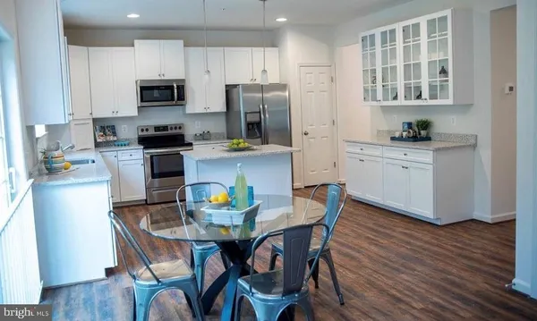 a kitchen with stainless steel appliances a dining table chairs microwave and stove top oven