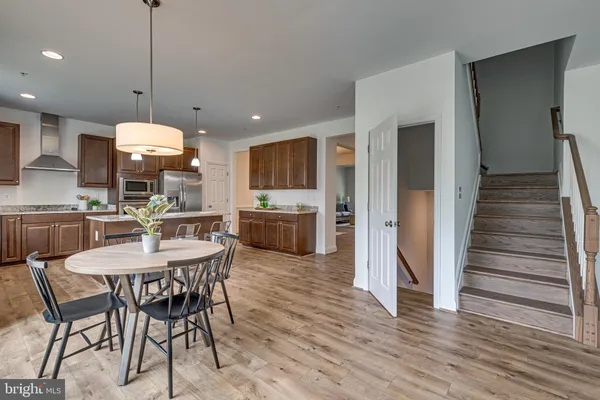 a kitchen with stainless steel appliances kitchen island granite countertop a stove a refrigerator and a dining table with wooden floor