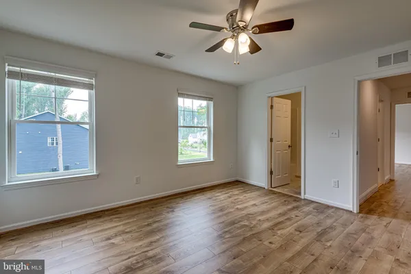 a view of empty room with wooden floor and fan