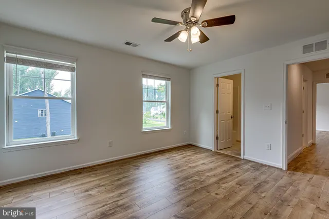 a view of empty room with wooden floor and fan