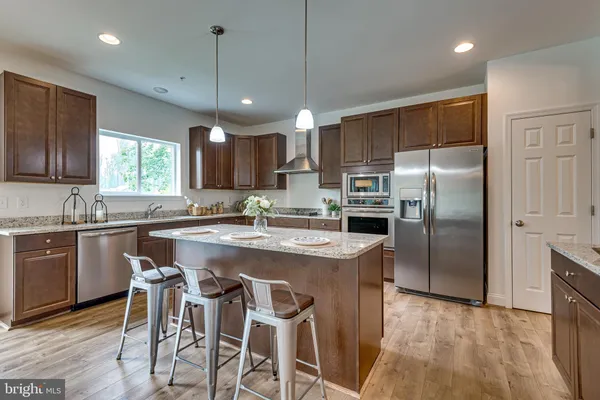 a kitchen with kitchen island granite countertop a sink a center island stainless steel appliances and cabinets
