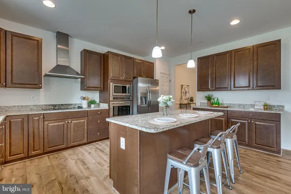 a kitchen with stainless steel appliances granite countertop a stove a sink a microwave a center island and chairs