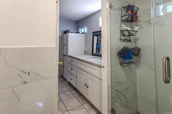 a bathroom with a granite countertop sink and a washing machine