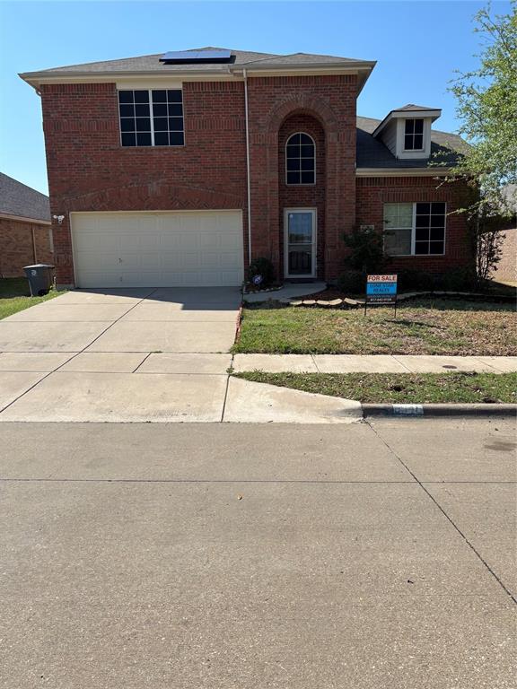 Traditional home featuring an attached garage, roof mounted solar panels, concrete driveway, and brick siding