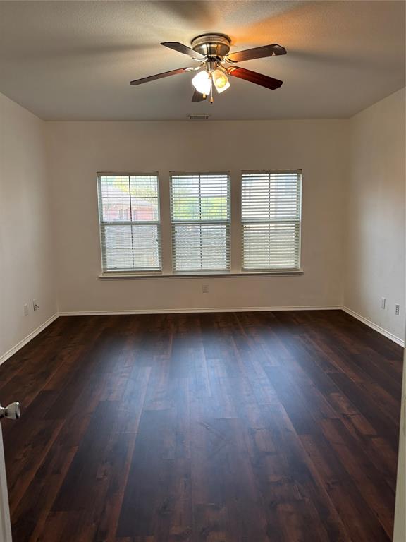 6546 Portside Ridge Lane Dallas, TX 75249 - Photo 19 of 35 Empty room featuring dark wood-style flooring, baseboards, a ceiling fan, and visible vents