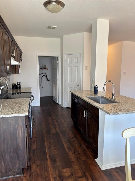 6546 Portside Ridge Lane Dallas, TX 75249 - Photo 31 of 35 Kitchen with stove, dark brown cabinetry, visible vents, dishwasher, and a sink