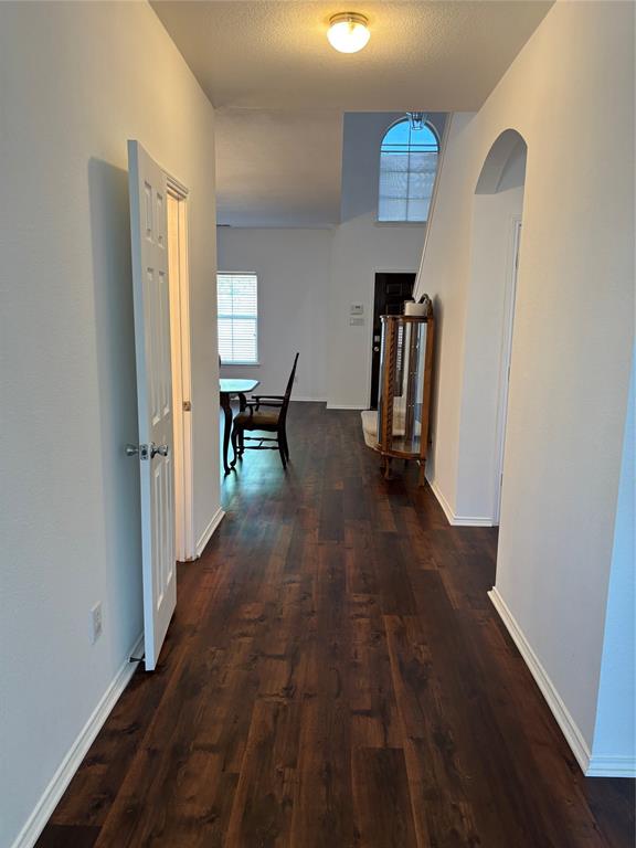 6546 Portside Ridge Lane Dallas, TX 75249 - Photo 8 of 35 Corridor with arched walkways, dark wood-type flooring, and baseboards