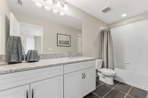 a bathroom with a granite countertop sink a toilet and a mirror