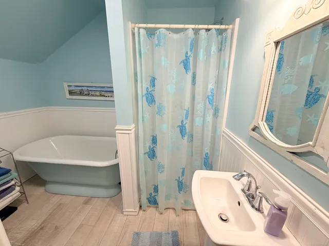 a bathroom with a tub a sink and a mirror