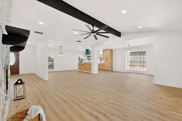 a view of an empty room with a window and wooden floor