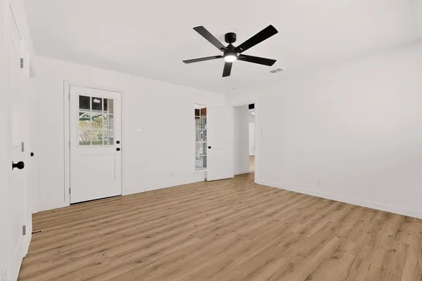 a view of a big room with wooden floor and windows