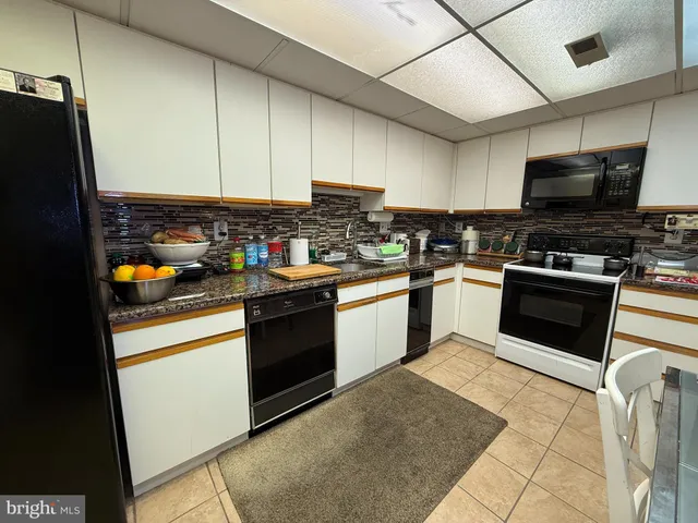 a kitchen with stainless steel appliances granite countertop a stove top oven a sink dishwasher and a refrigerator with wooden cabinets