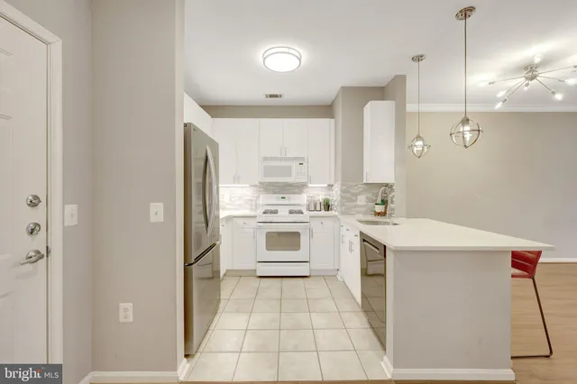 a kitchen with a sink dishwasher and a refrigerator with wooden floor