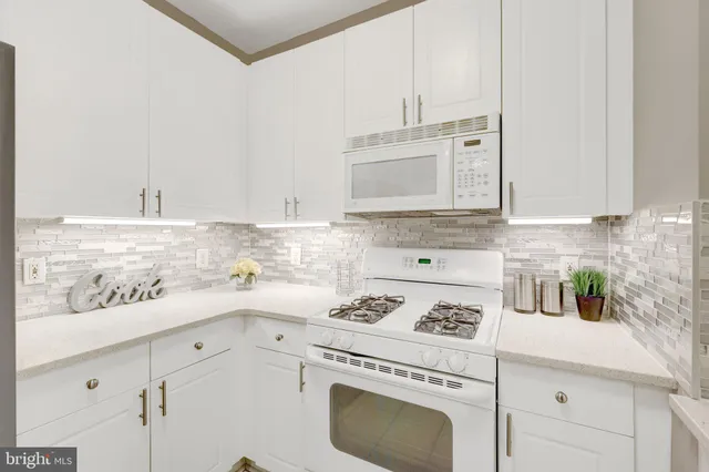 a kitchen with stainless steel appliances white cabinets and a stove top oven