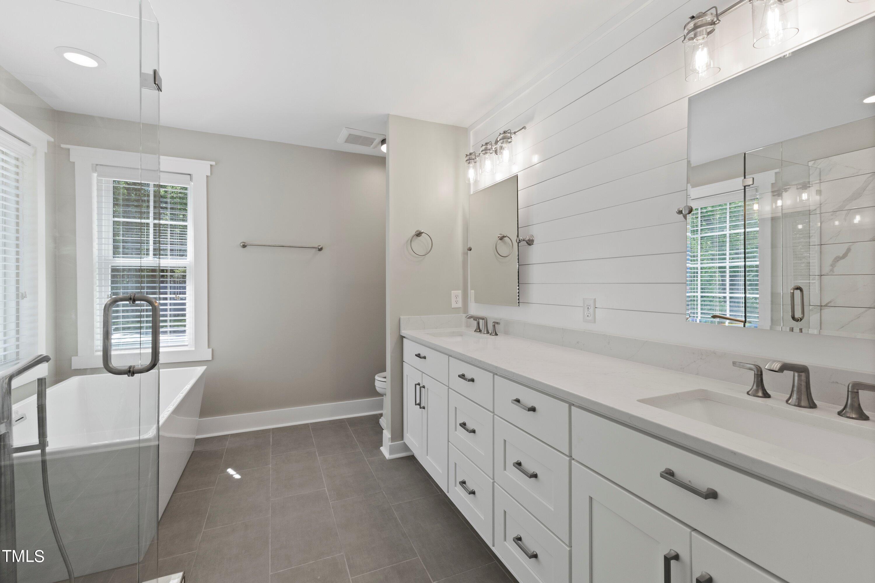 7408 Lakefall Drive Wake Forest, NC 27587 - Photo 30 of 65 a bathroom with double vanity sink a two mirror a window and glass door