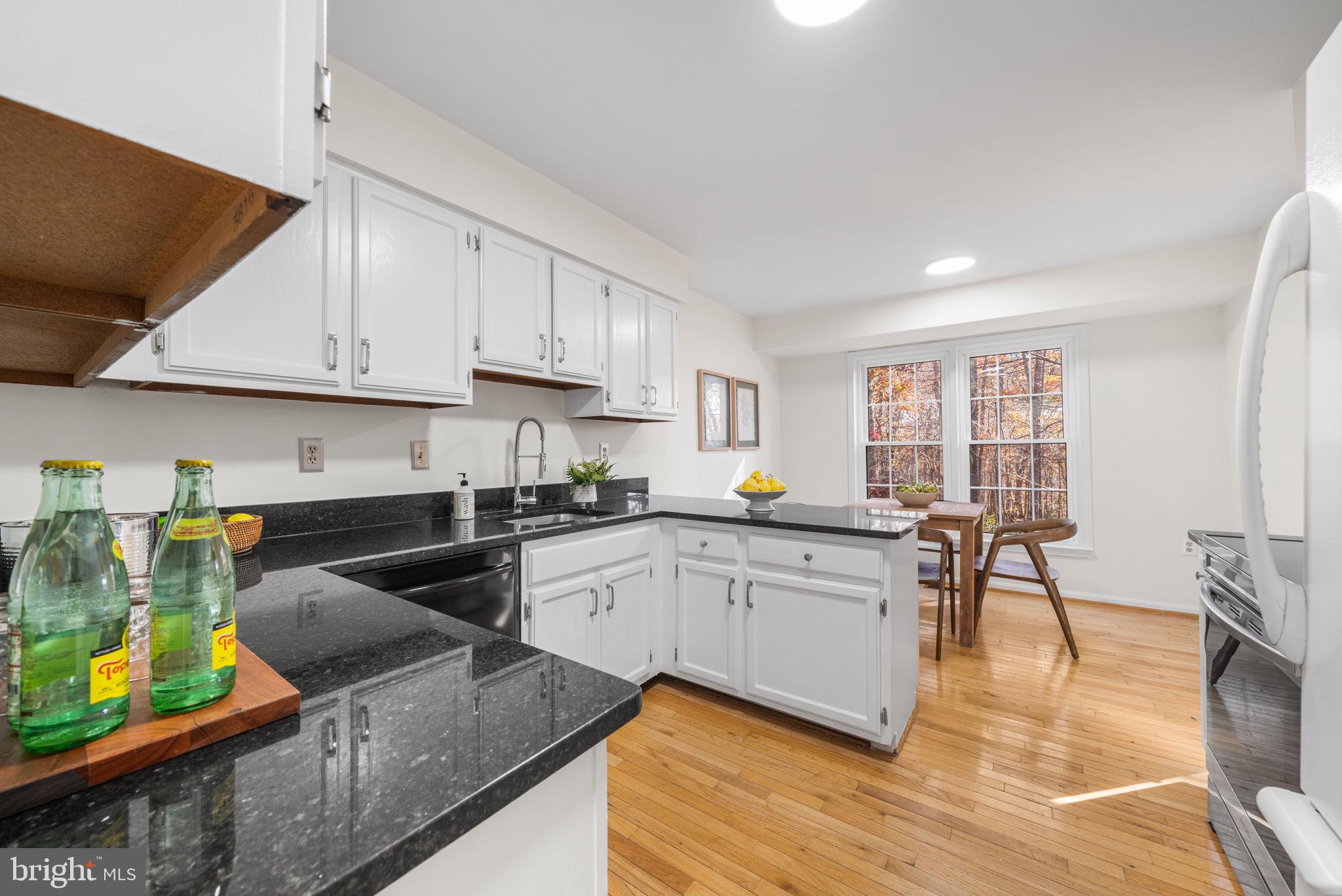 5658 Sutherland Court Burke, VA 22015 - Photo 11 of 30 a kitchen with stainless steel appliances granite countertop a stove top oven a sink a dining table and chairs with wooden floor