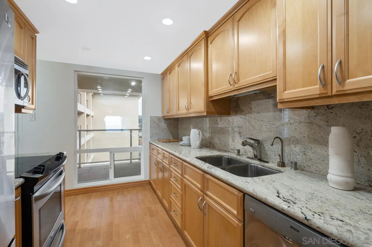 939 Coast Boulevard, Unit 20C La Jolla, CA 92037 - Photo 11 of 25 a kitchen with granite countertop a sink a stove and cabinets