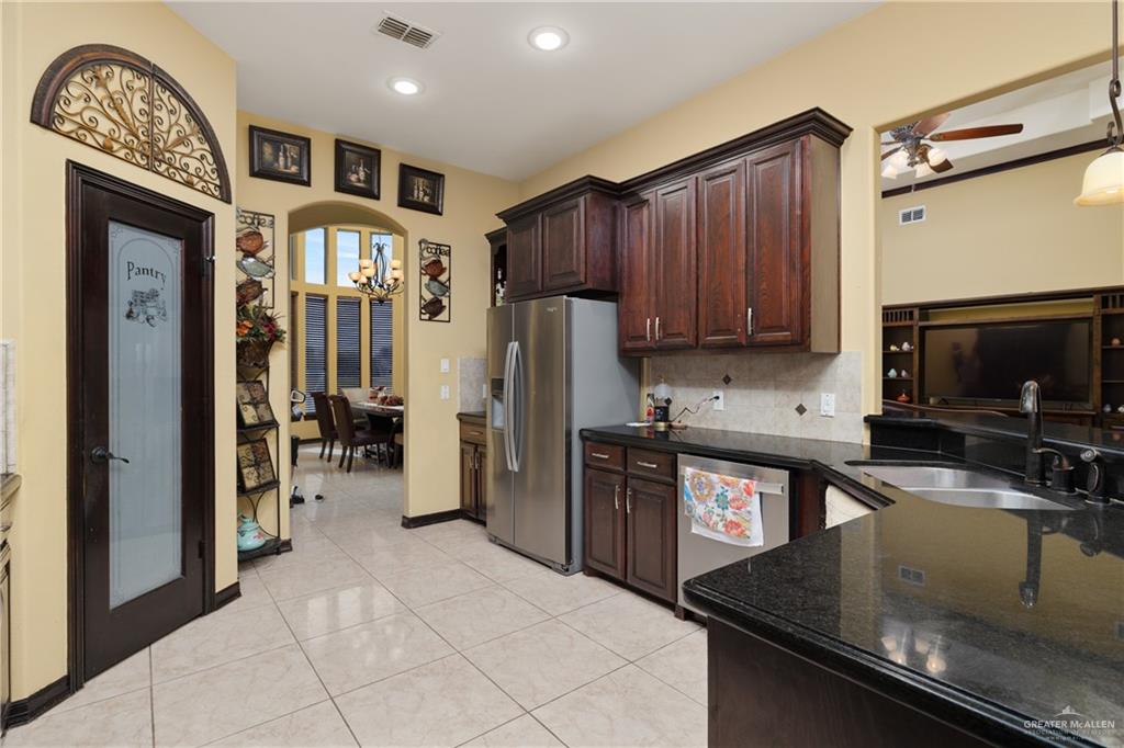 1502 Eucalyptus Street Weslaco, TX 78599 - Photo 7 of 24 a kitchen with stainless steel appliances granite countertop a refrigerator a stove and a sink with wooden cabinets