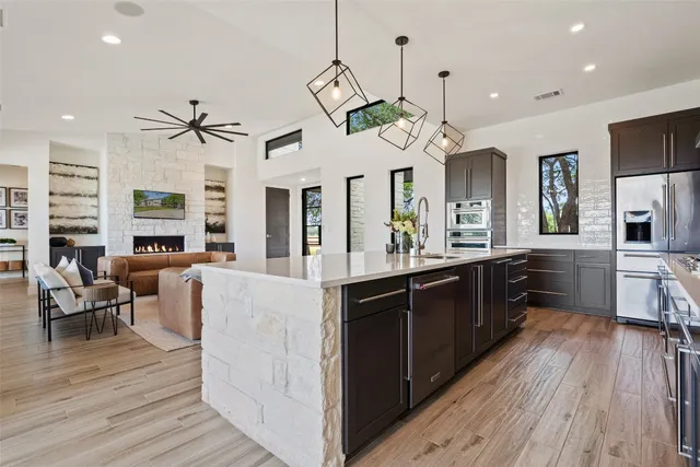 a kitchen with stainless steel appliances kitchen island granite countertop a table chairs in it and wooden floors
