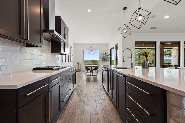 a kitchen with stainless steel appliances granite countertop a refrigerator a sink dishwasher a dining table and chairs with wooden floor