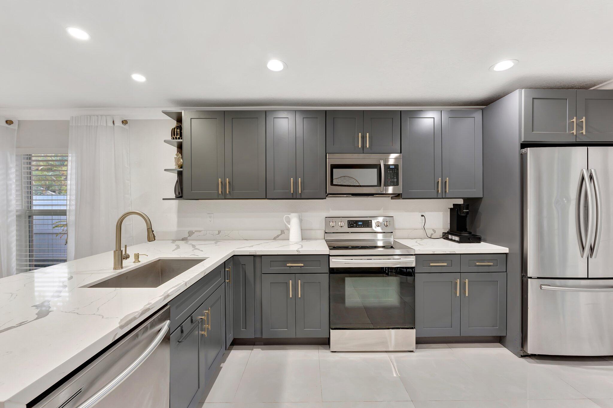 4901 Lincoln Road Delray Beach, FL 33445 - Photo 15 of 56 a kitchen with a sink a stove a refrigerator and a center island