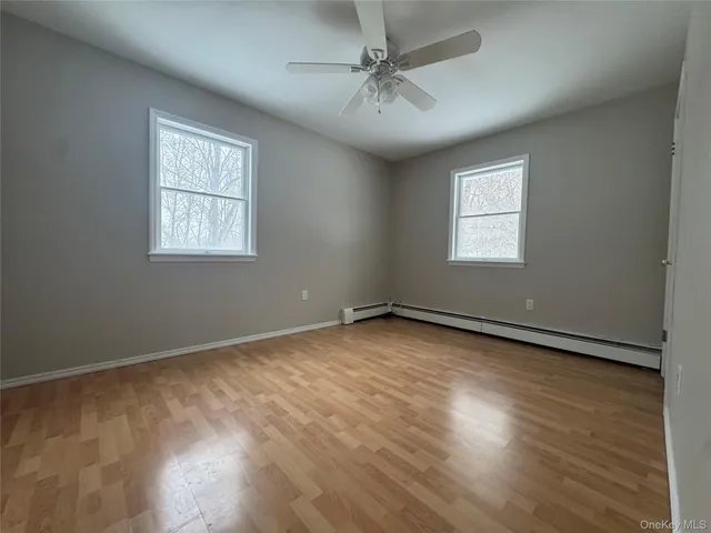a view of an empty room with a window and wooden floor