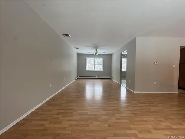 a view of empty room with wooden floor and window