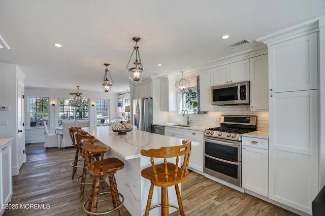 a kitchen with stainless steel appliances a stove a sink cabinets and a dining table