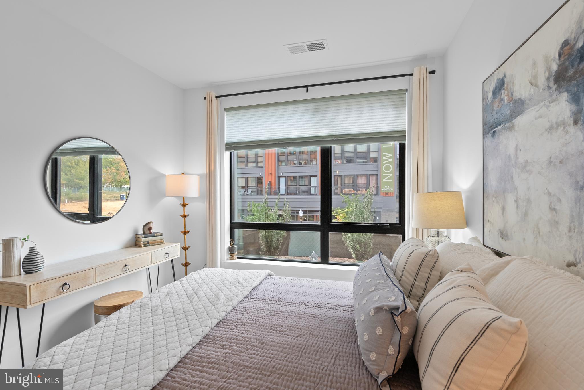 7175 12th Street Northwest, Unit 214 Washington, DC 20012 - Photo 18 of 49 a bedroom with a bed a mirror and a large window with outer view