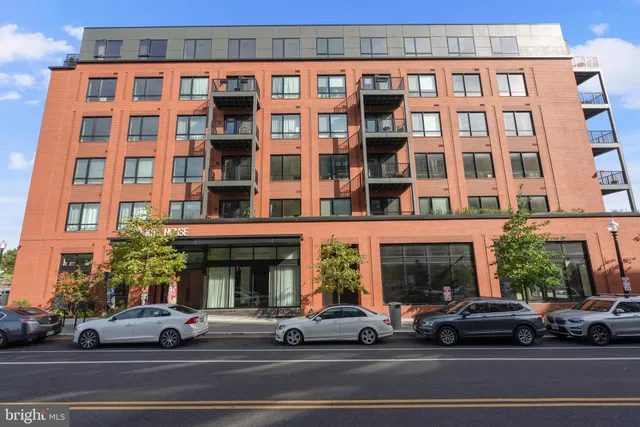 a view of a building and car parked on the side of road