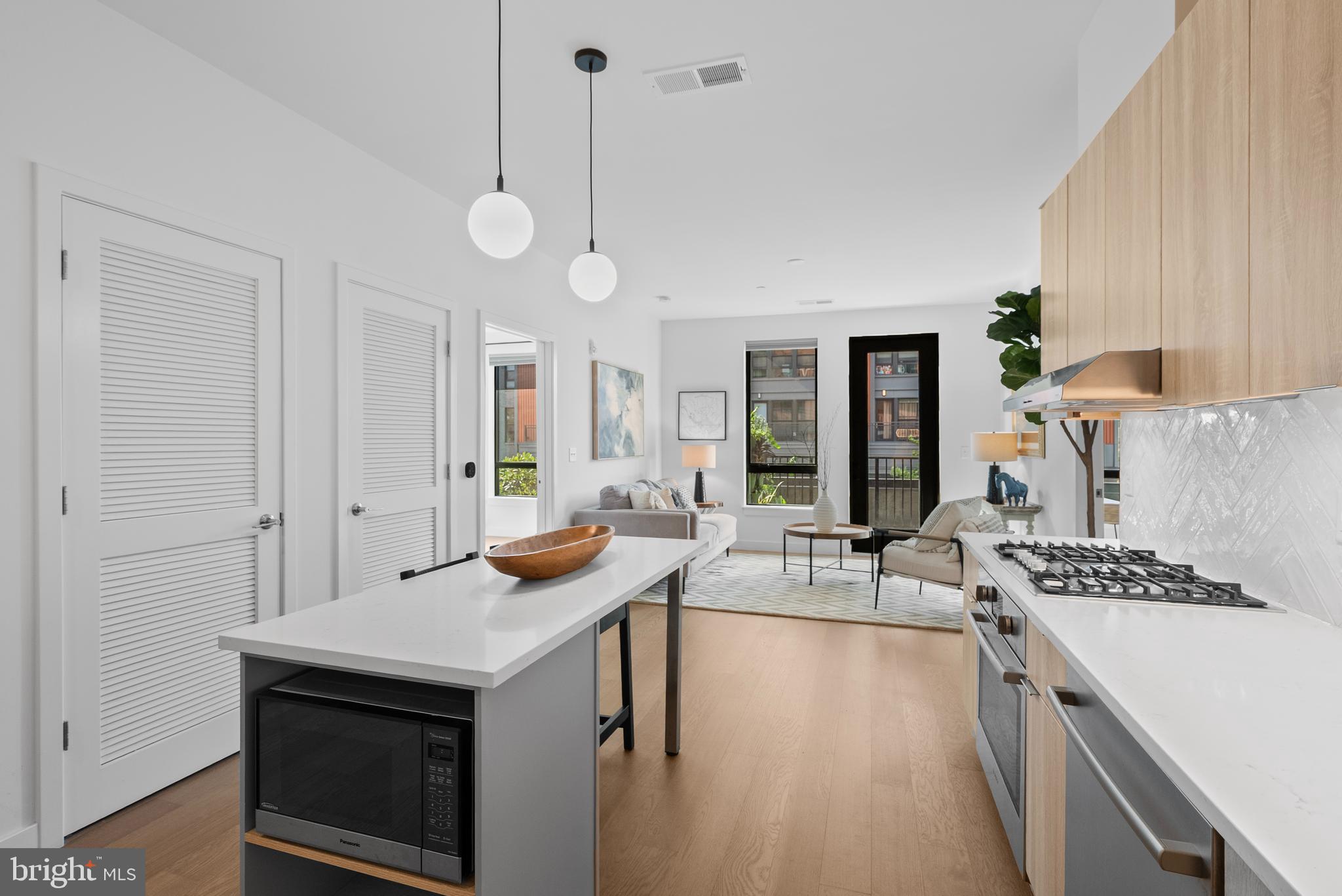 7175 12th Street Northwest, Unit 214 Washington, DC 20012 - Photo 5 of 49 a open kitchen with stainless steel appliances granite countertop a stove and a sink with couches