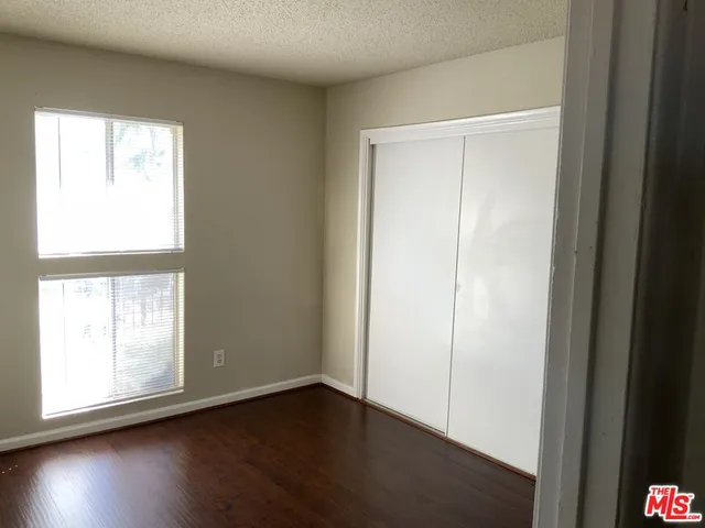 an empty room with wooden floor closet and windows