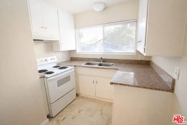 a kitchen with granite countertop white cabinets and white appliances