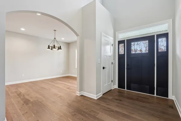 a view of an empty room with wooden floor and a ceiling fan