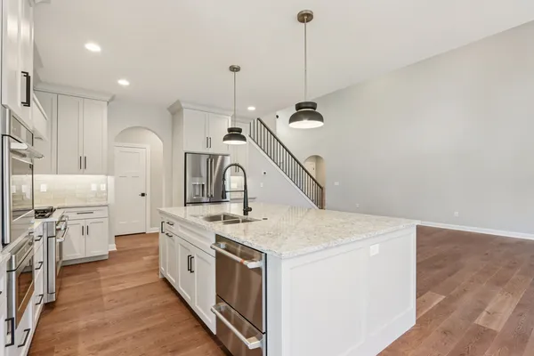 a kitchen with stainless steel appliances granite countertop a sink a stove and a wooden floors