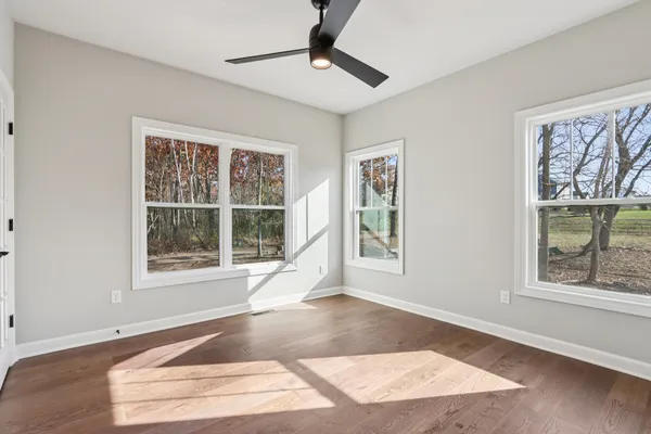 a view of an empty room with a window and wooden floor