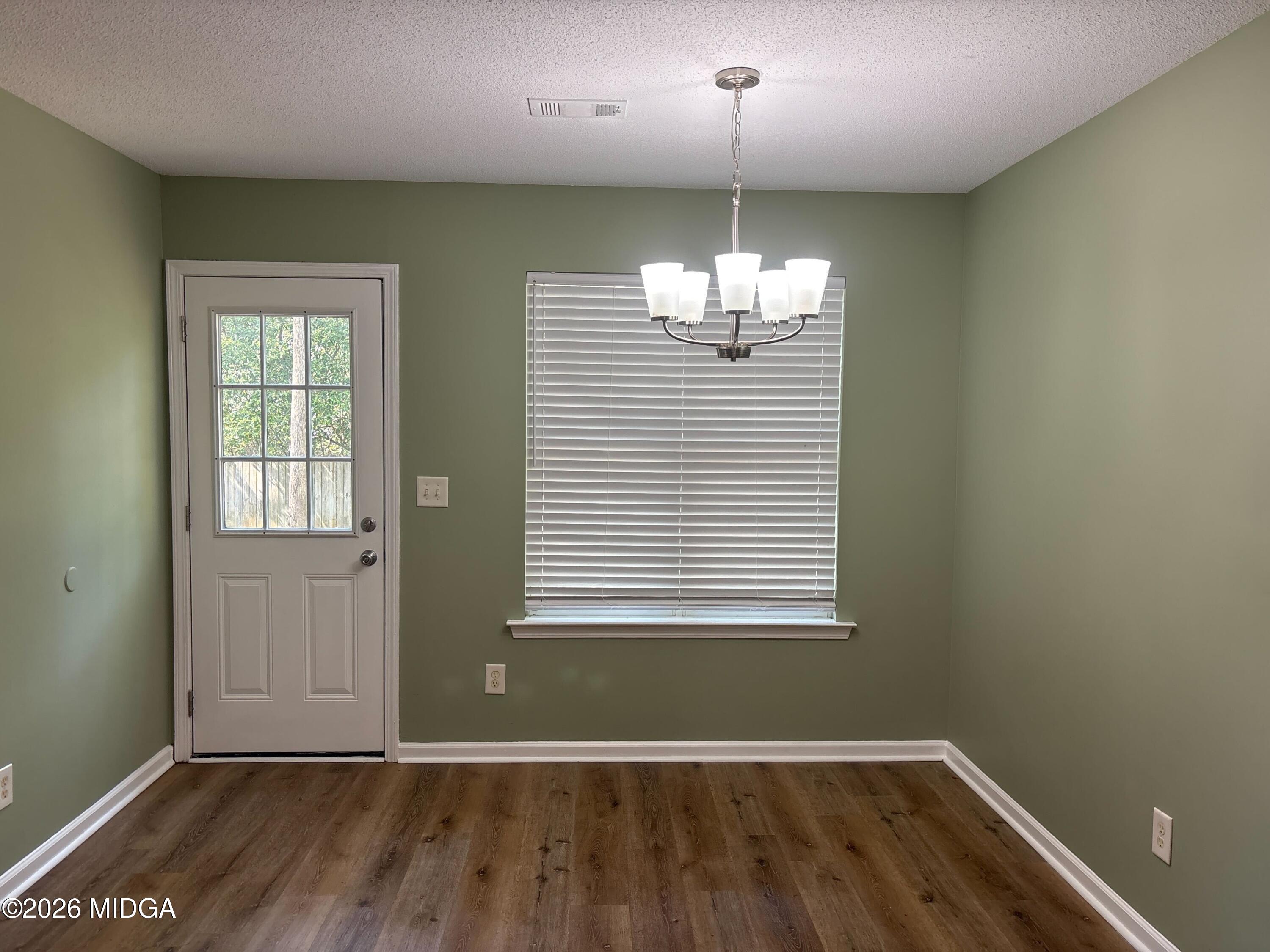 404 Dunmurry Place Warner Robins, GA 31093 - Photo 7 of 18 an empty room with wooden floor chandelier and windows