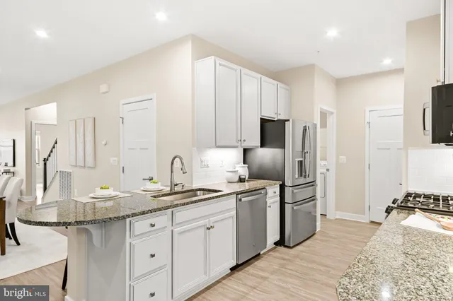 a large kitchen with stainless steel appliances granite countertop a sink stove refrigerator and cabinets
