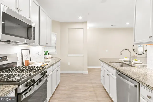 a kitchen with stainless steel appliances granite countertop a sink a stove a refrigerator and cabinets