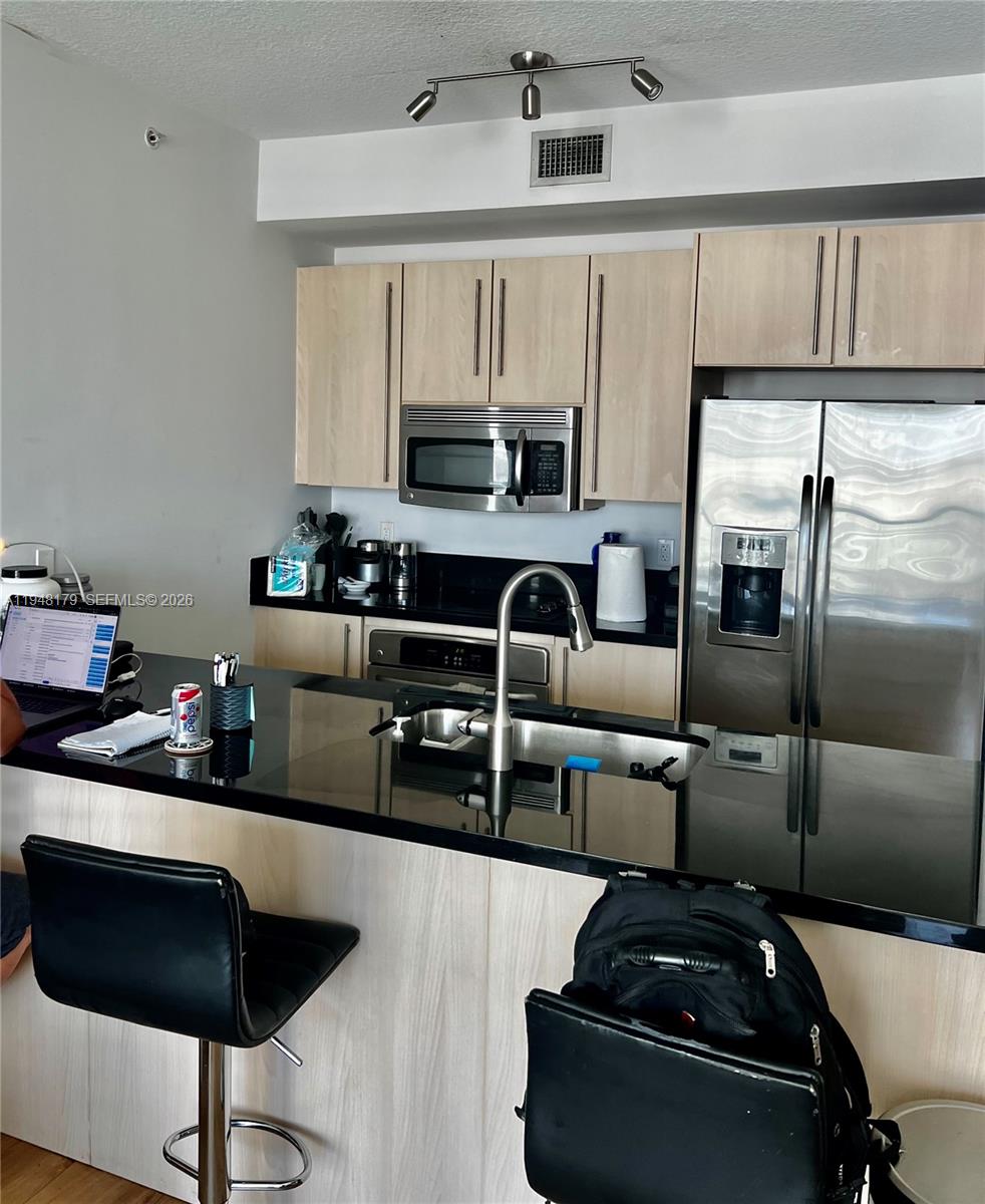 79 Southwest 12th Street, Unit 3008S Miami, FL 33130 - Photo 7 of 11 a kitchen with stainless steel appliances granite countertop a stove a sink and a refrigerator