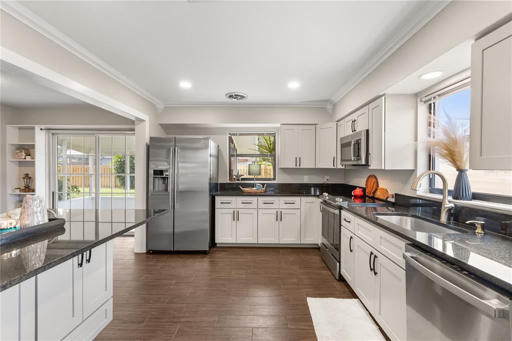 660 Java Road Cocoa Beach, FL 32931 - Photo 13 of 31 a kitchen with stainless steel appliances granite countertop a refrigerator a sink dishwasher a oven with white cabinets and wooden floor