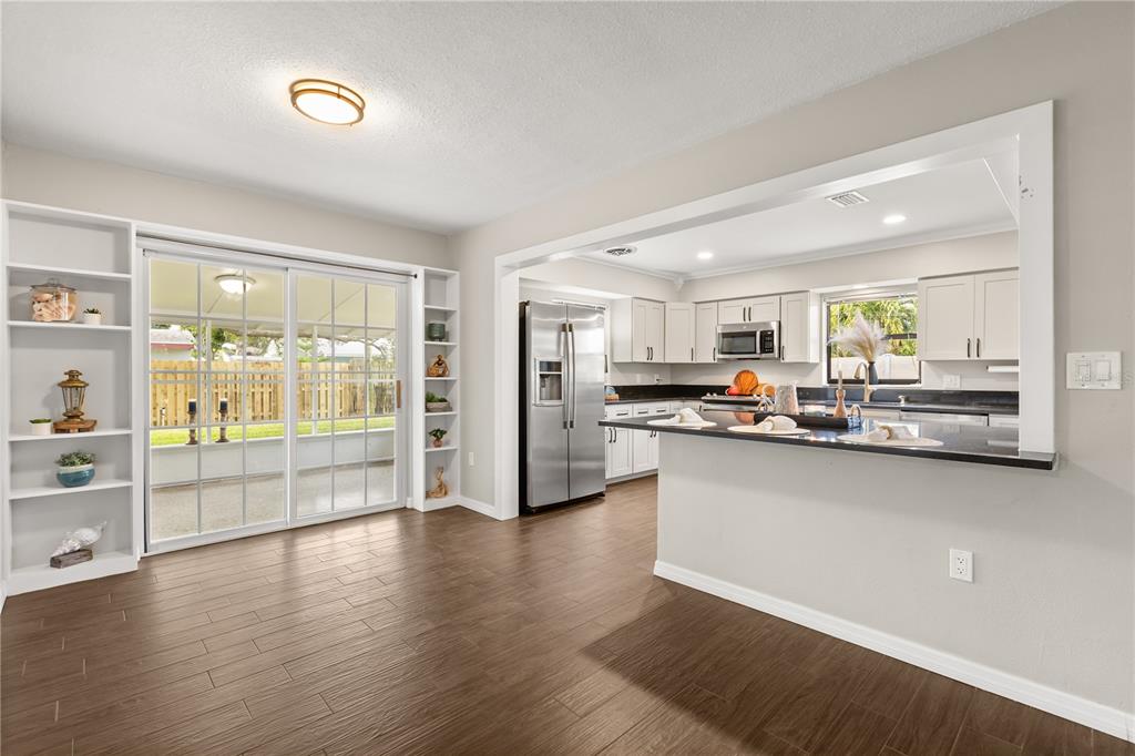 660 Java Road Cocoa Beach, FL 32931 - Photo 8 of 31 a living room with stainless steel appliances kitchen island granite countertop a refrigerator a stove a sink and a dining table with wooden floor