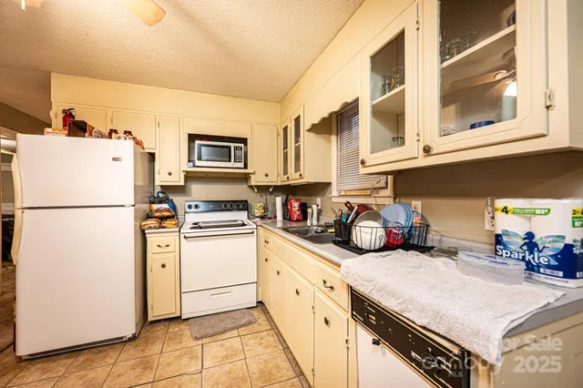 a kitchen with stainless steel appliances granite countertop a refrigerator sink stove and white cabinets