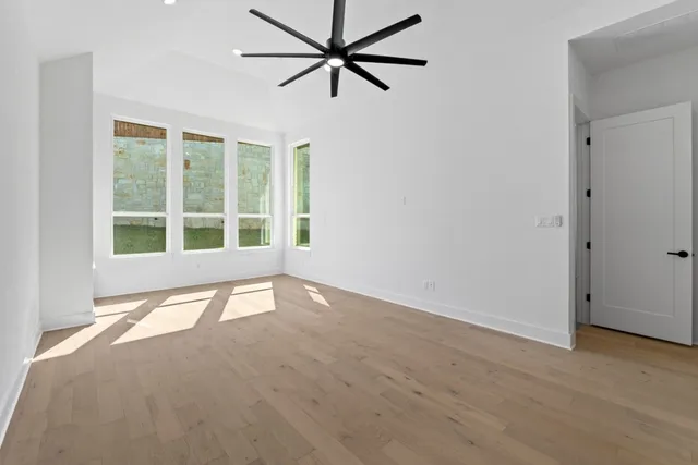 a view of an empty room with wooden floor and a kitchen