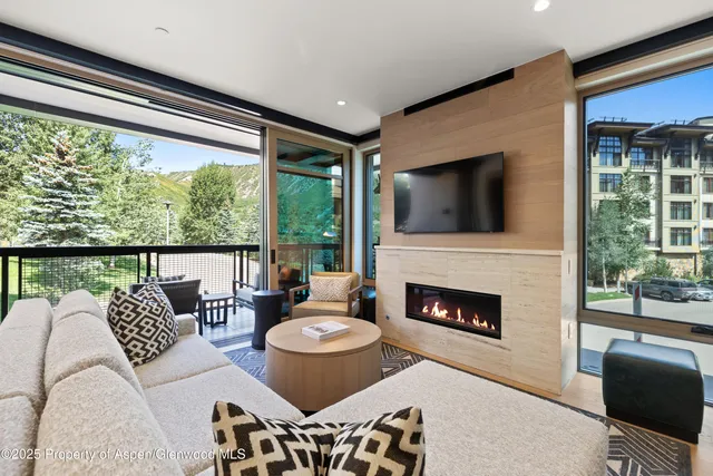 a living room with furniture a fireplace and a floor to ceiling window
