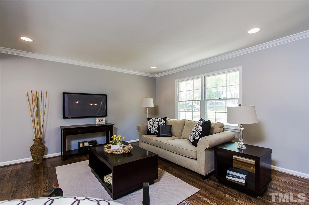 7617 Elliot Drive Raleigh, NC 27613 - Photo 5 of 25 a living room with furniture a fireplace and a flat screen tv